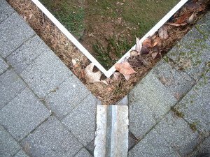 Corner debris pulled from a downspout mouth — this is what causes the puddling you see on the walkway below.